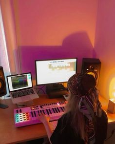 a person sitting at a desk with two computers and headphones on, in front of them