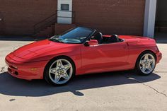 a red sports car parked in front of a brick building