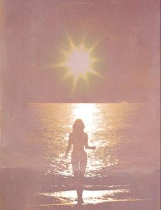 a woman is standing in the water at sunset