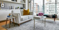 a living room filled with furniture next to a window covered in lots of books and vases