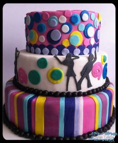 three tiered cake decorated with multi - colored fondant and polka dot design on top