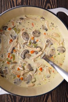 a pot filled with chicken and mushroom soup on top of a wooden table