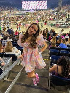 a girl in a pink dress is standing on the bleachers