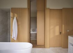 a white bath tub sitting in a bathroom next to a wooden cabinet and counter top