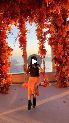 a woman in an orange skirt and black t - shirt is dancing on a balcony