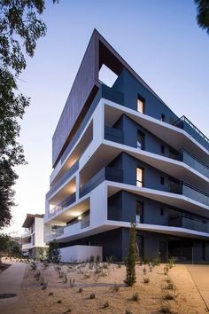 an apartment building with multiple balconies on the top and bottom floors is shown at dusk