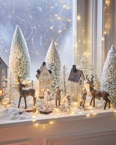 a window sill filled with christmas decorations and figurines on top of snow covered ground