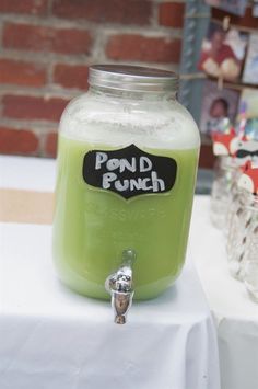 a green drink in a mason jar on top of a white table cloth next to a brick wall