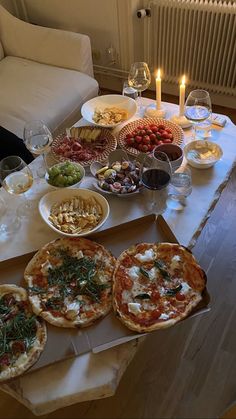 pizzas and other food on a table with candles