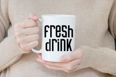 a woman holding a coffee mug with the words fresh drink printed on it in black