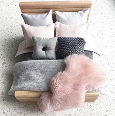 a bed topped with pillows and blankets next to a wooden headboard on top of a white floor