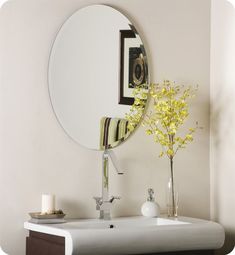 a white sink sitting under a mirror next to a vase with flowers in front of it