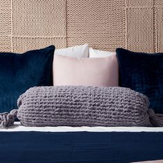 a bed topped with pillows and blankets next to a headboard covered in wicker