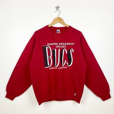 90s Dawson Community College Bucs Crewneck Sweatshirt Print Logo Red Color Men's L - Made in Mexico - Materials : Cotton, Polyester  - Tag Reads : L Kindly see the actual measurements (All measurements were taken lying flat) - Actual size manual measurements * Width (Armpit to armpit) : 23 inches * Length (Shoulder to end of garment) : 26 inches * Sleeve length : 23 inches - Condition : * Vintage condition 9/10 (90%) * Free from stain tear and major defect - Shipping : * DHL Express/FedEx Express = 3-6 business day arrived * Please PROVIDE your PHONE/CONTACT NUMBER for SHIPPING/DELIVERY purpose DON'T FORGET TO VISIT MY SHOP FOR MORE GREAT STUFF, THANK YOU. Vintage Red Crew Neck Tops, Vintage Red Crew Sweatshirt, Red Vintage Crew Sweatshirt, 90s Red Cotton Sweatshirt, 90s Style Red Sweatshirt With Letter Print, 90s Red Letter Print Sweatshirt, 90s Style Red Letter Print Sweatshirt, Vintage Red T-shirt For Winter, Retro Red Cotton Sweatshirt