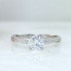 a white gold engagement ring with diamonds on the band and a round brilliant cut diamond in the center