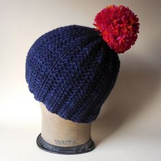 a knitted hat with a red and blue pom - pom on top