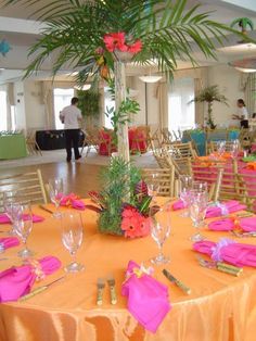 an orange table cloth with pink napkins and place settings is set up for a formal function