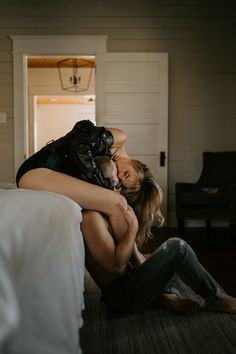 a woman sitting on the floor hugging another woman's head while she is in bed