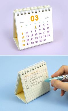 a desk calendar with a pen sticking out of it and someone writing on the page