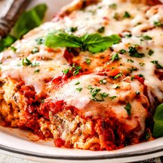 a white plate topped with lasagna covered in sauce and cheese