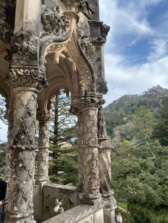 an old building with stone pillars and carvings on the outside, overlooking a mountain range