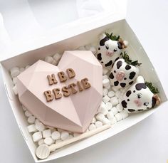 a heart shaped cake in a box with marshmallows and other decorations around it