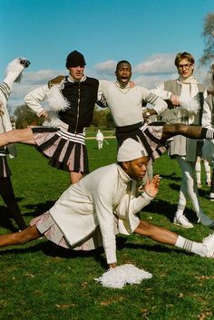 a group of men and women dressed in costume posing for a photo on the grass