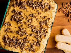 a casserole dish with pecans and pumpkins next to it on a wooden table