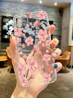 a woman holding up her phone case with pink flowers on it