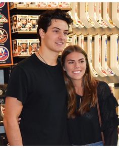 a man and woman standing next to each other in front of video game cases at a store