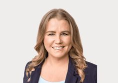 a woman with long blonde hair wearing a blue blazer and smiling at the camera