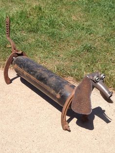 an old metal dog sculpture sitting on the ground