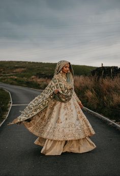 a woman in a wedding dress is walking down the road with her veil over her head