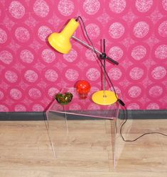 a table with two lamps on it and some fruit in front of a pink wall