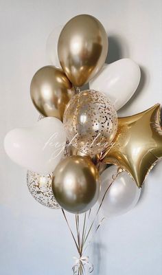 gold and white balloons are arranged in a vase