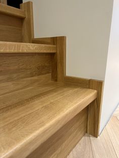 a wooden stair case next to a white wall