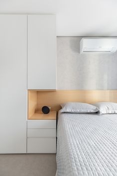 a white bed sitting next to a wall mounted air conditioner