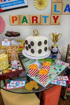 a birthday party with a cake, popcorn and other snacks on the table in front of it