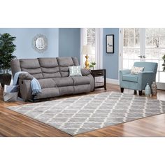 a living room filled with furniture and a rug on top of a hard wood floor