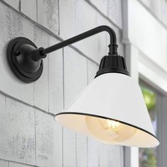 a white and black lamp on the side of a wall next to a brick building