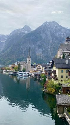 a lake with houses and boats in the water next to some mountain range behind it