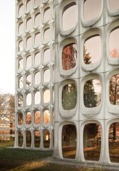 an unusual building with many windows on the side and trees in the backgroud