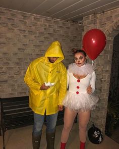 two people dressed in costumes standing next to each other and one holding a red balloon