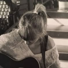 a woman sitting on the steps playing an acoustic guitar