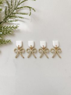 three white candles with bows on them next to a pine branch and evergreen branches in the background