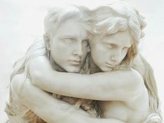 two white statues hugging each other with their arms wrapped around one another's shoulders