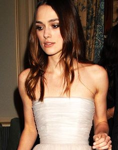 a woman in a strapless white dress is holding a piece of cake