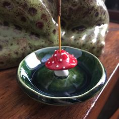 a small red mushroom sitting on top of a green bowl