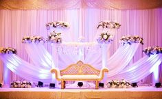 an elegant wedding setup with white flowers and purple drapes