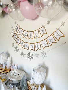 a dessert table with balloons and snowflakes on the wall in front of it